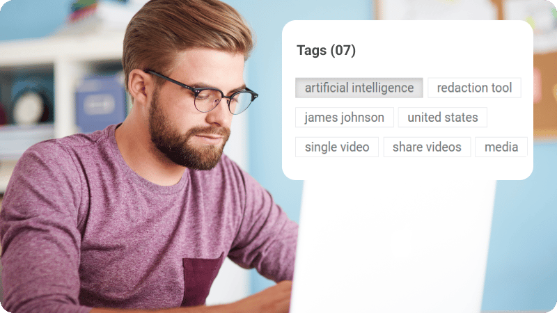 A man in glasses watching a video on his laptop.