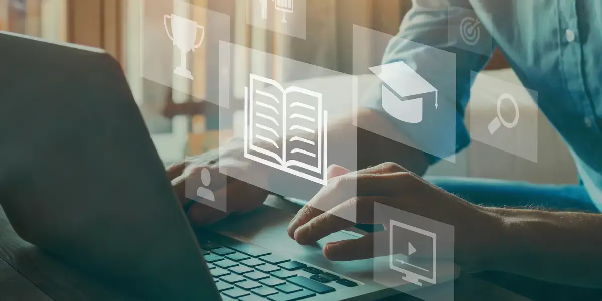 A person typing on a laptop with icons representing learning, education, and technology floating around, symbolizing the power of video-based learning for courses.