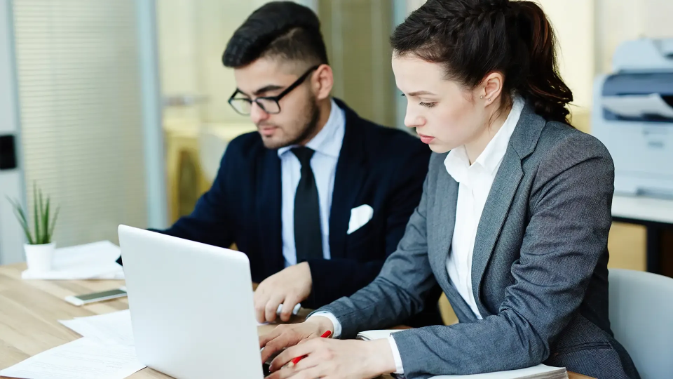 Two banking officials working on a laptop