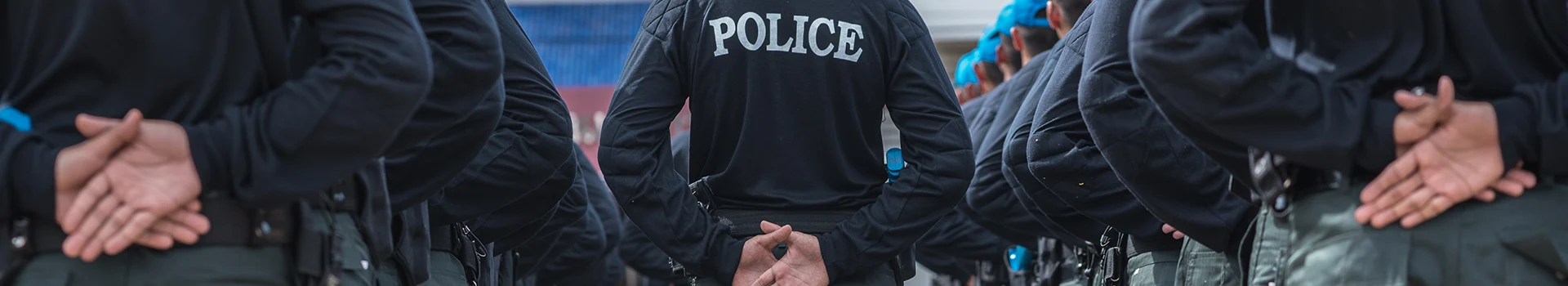 A police officer standing with his hands folded backwards.