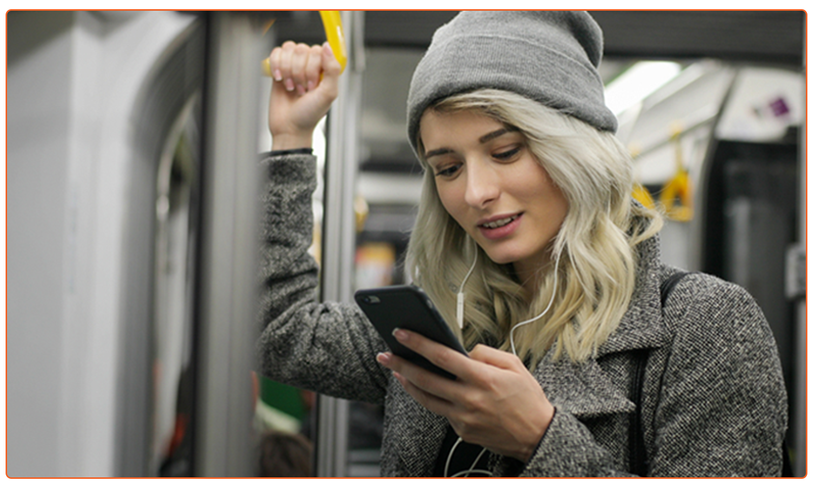 A woman enjoying video streaming on a smartphone on a subway train.