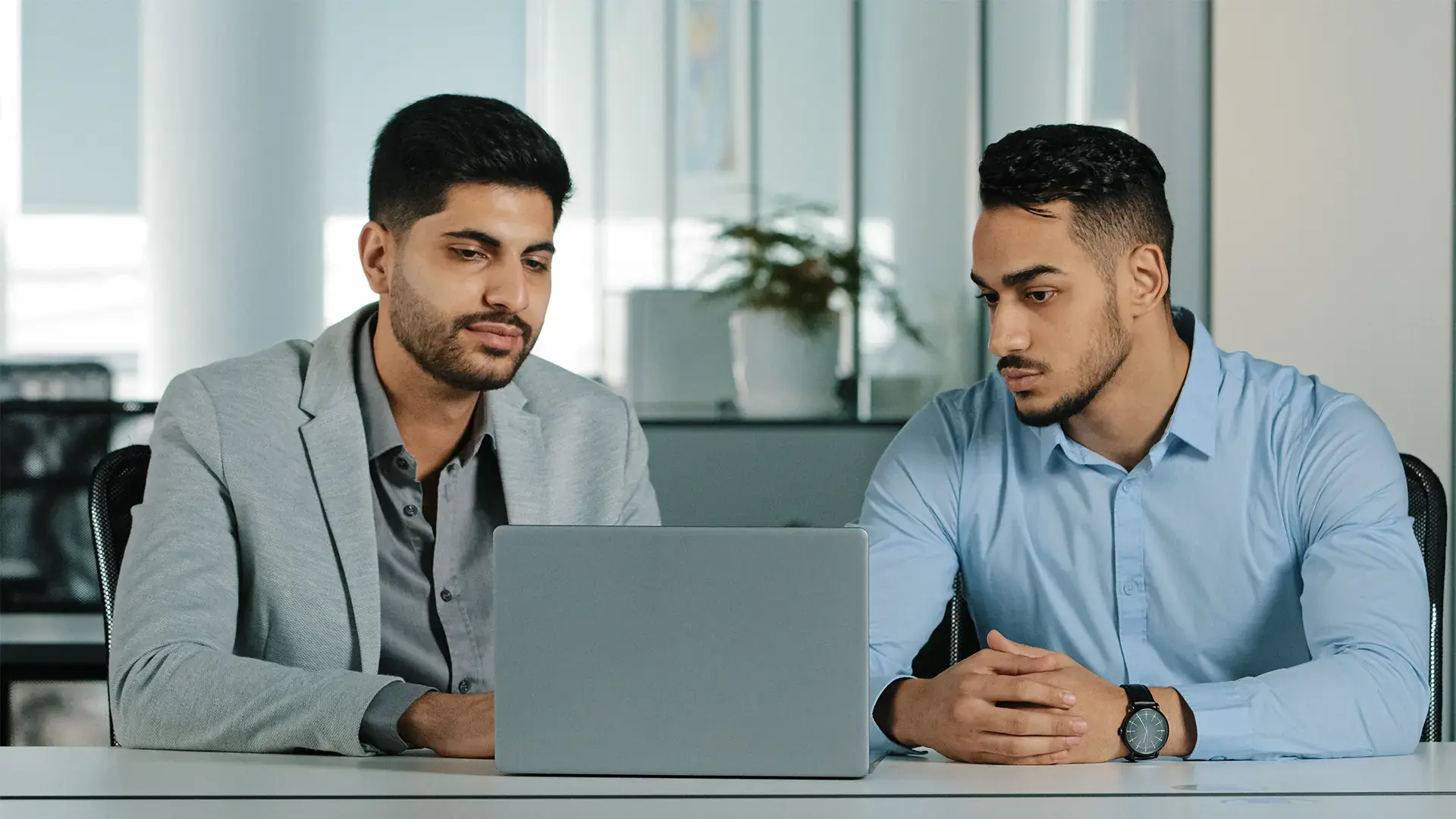 Two professionals reviewing AI-analyzed results on a laptop in an office.