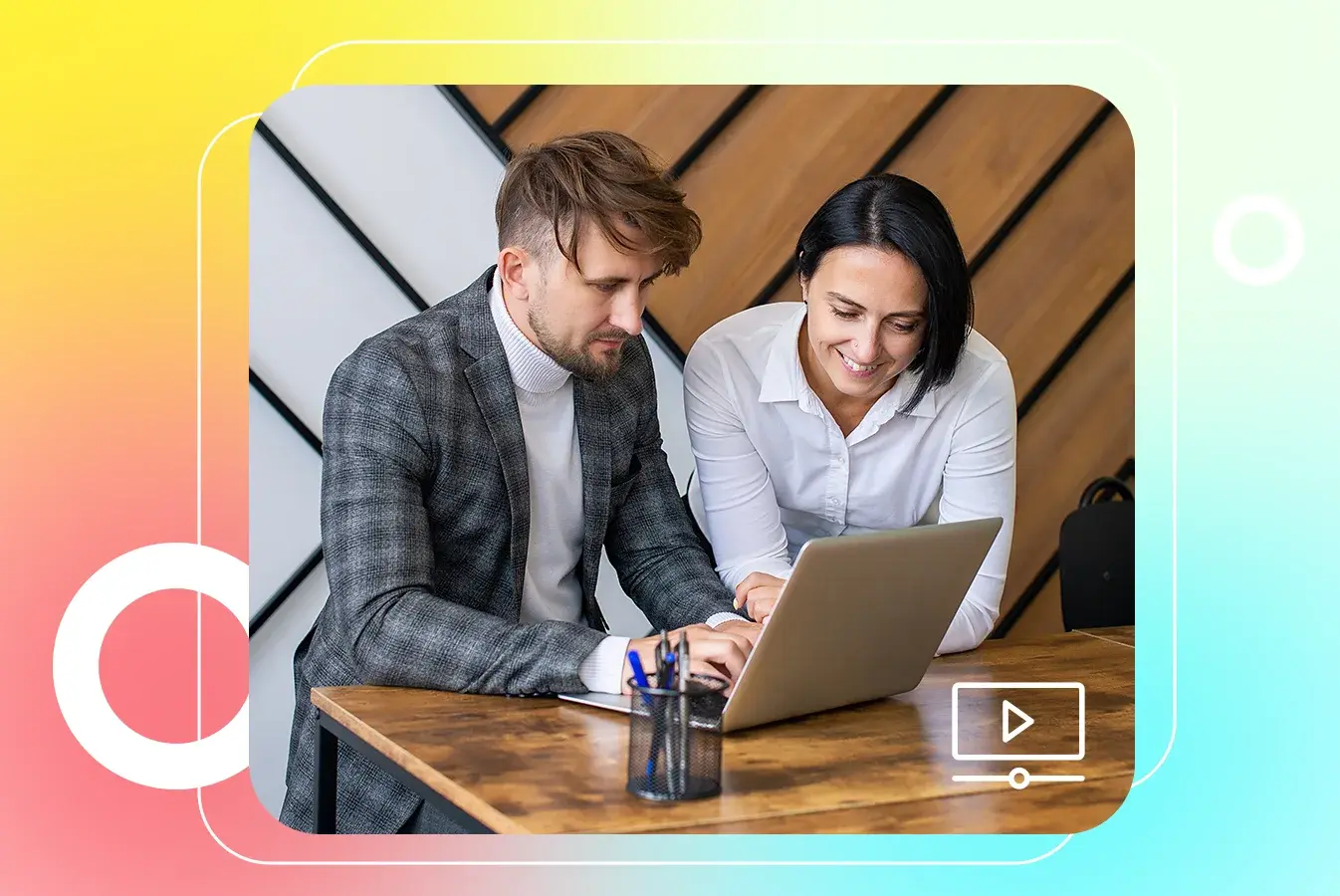 Two employees using a laptop to setup a video content management system 