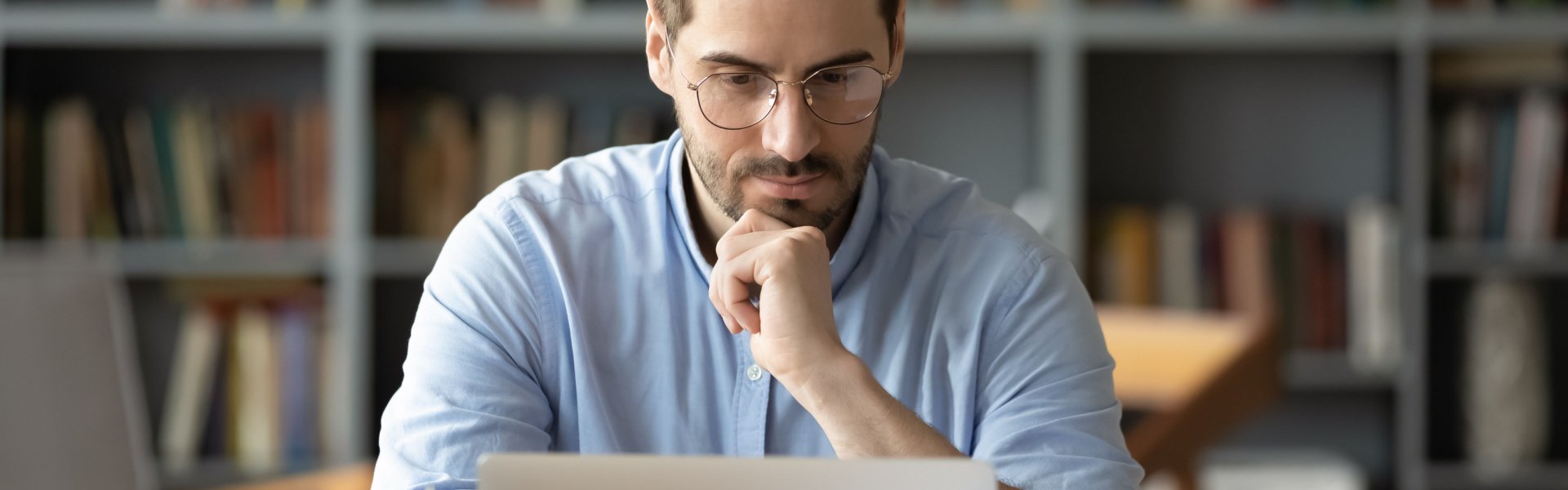 Man working on a system in a focused position, reading closed captions or subtitles.