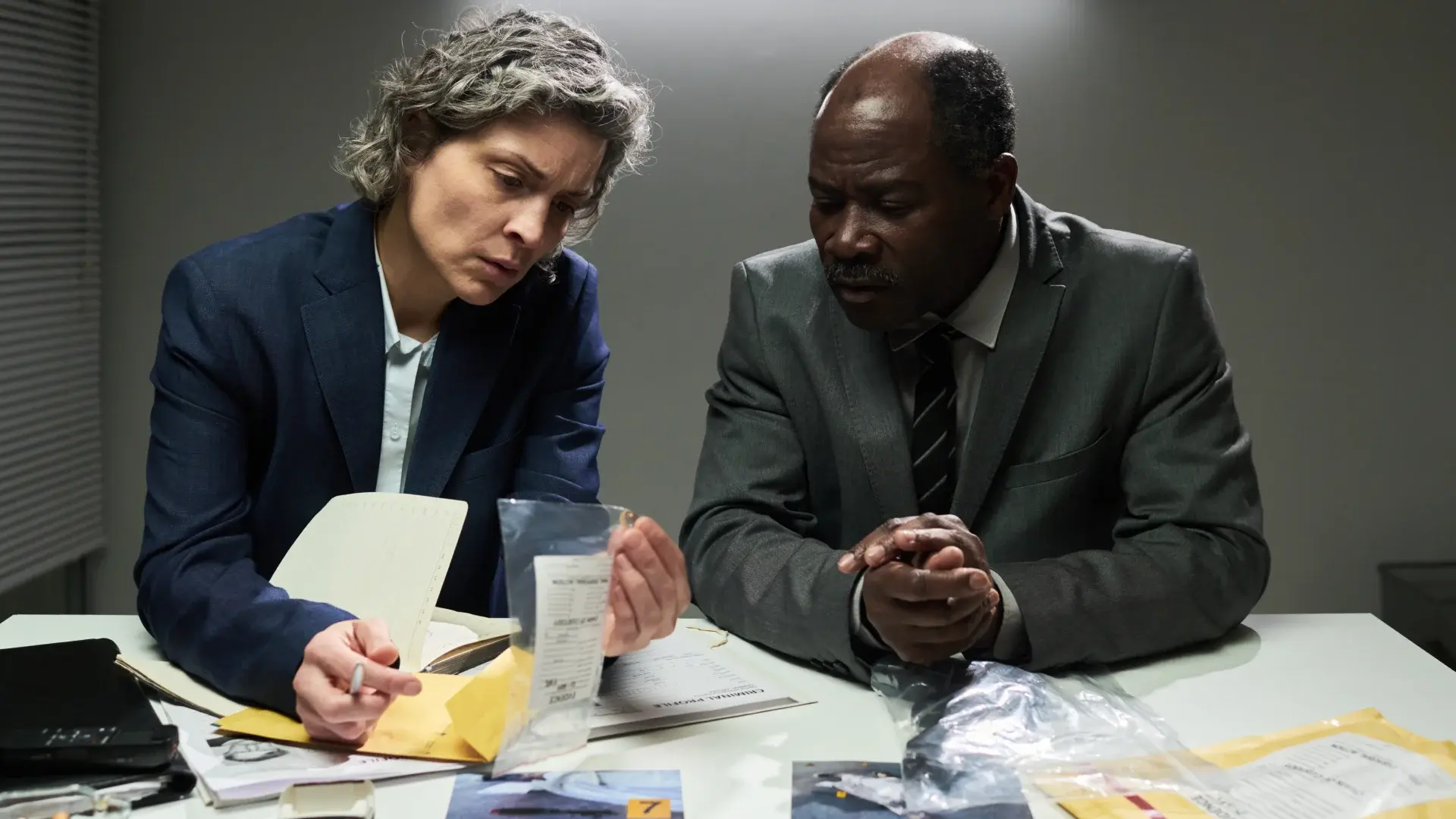 Investigators reviewing sealed evidence and case documents at a table