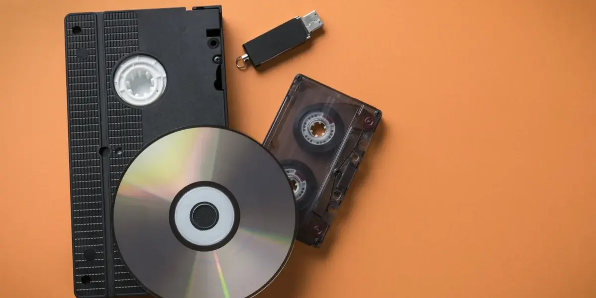 Various traditional storage media including a VHS tape, a CD, a USB flash drive, and a cassette tape, representing the evolution of video and data storage technologies.