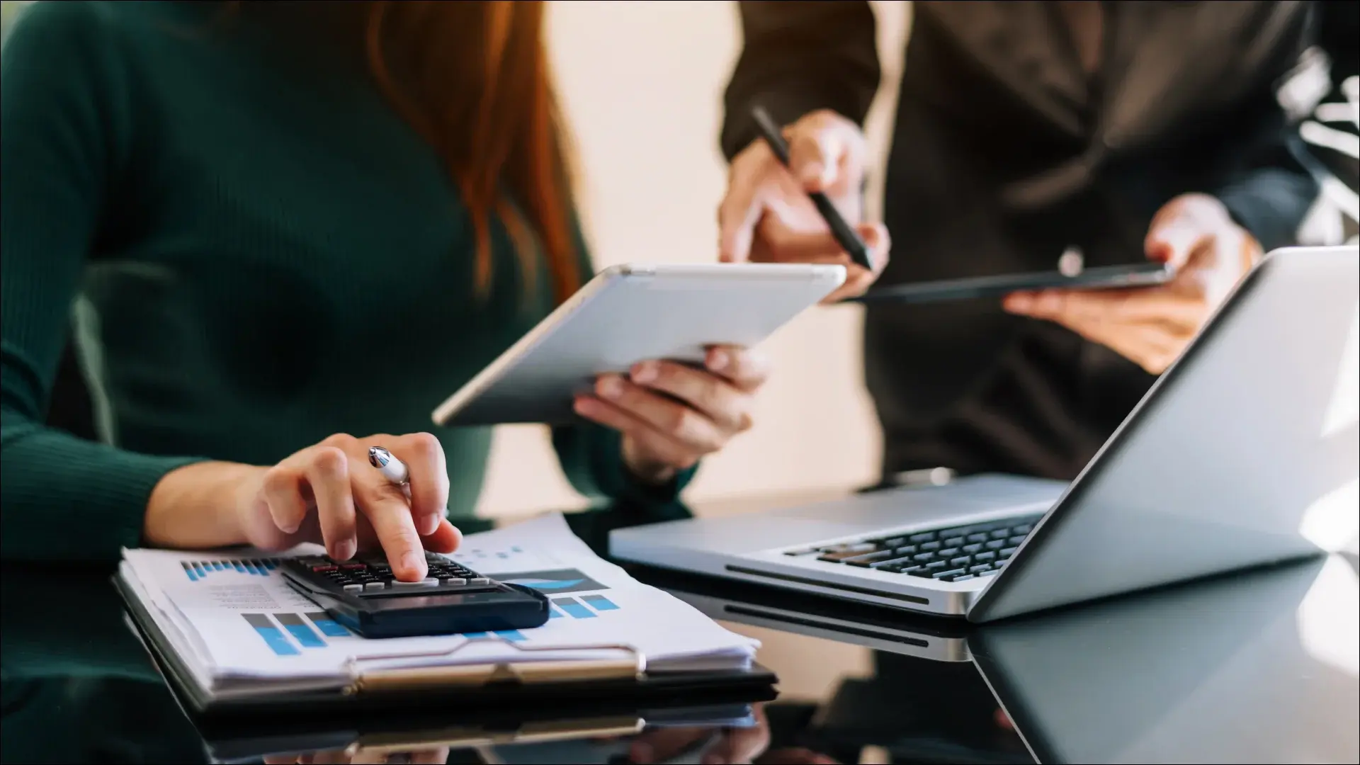 A banking professional working on a calculator and a laptop