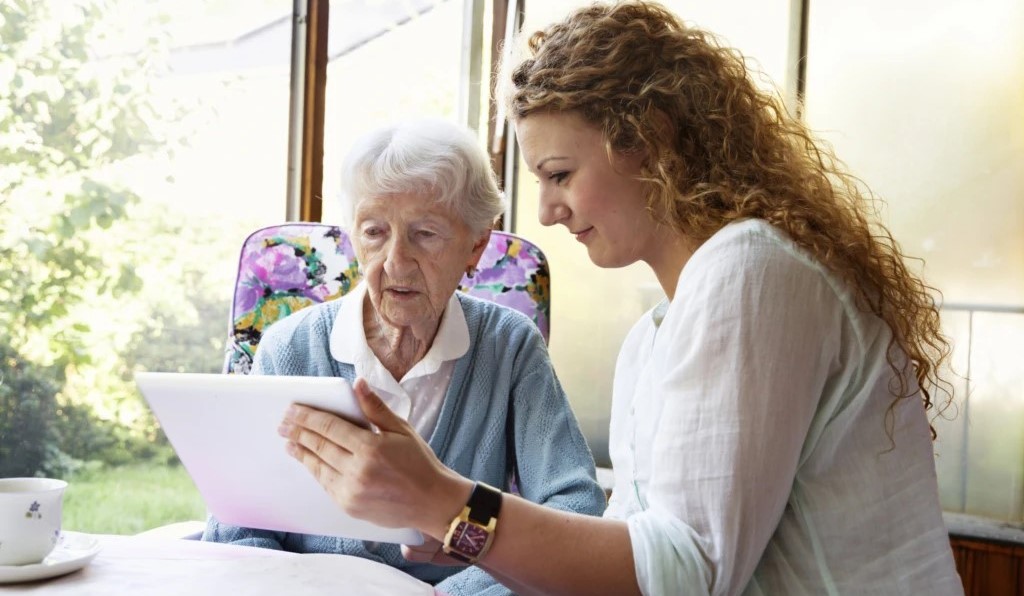 a woman interacting with an old lady and showing her reports