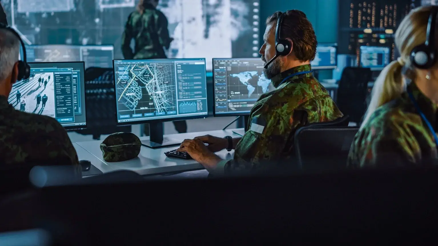 Military personnel analyzing data on multiple screens, demonstrating the efficiency of law enforcement digital evidence management with secure, AI-powered solutions.