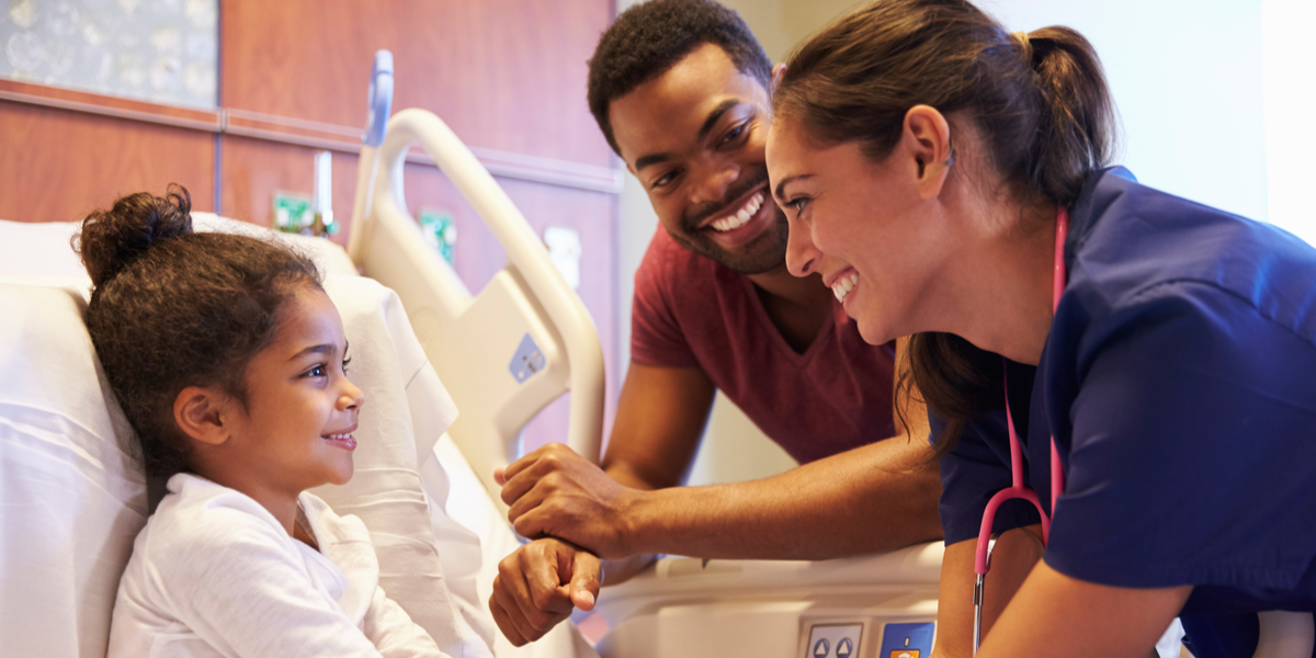 A healthcare staff smiling at patient and her family member