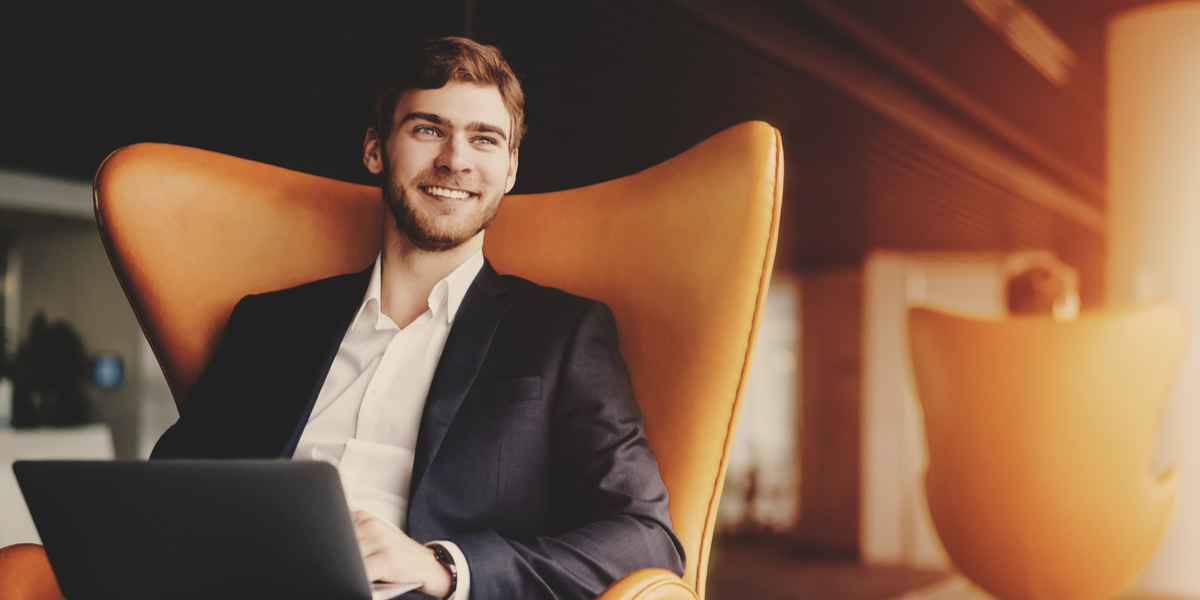 A man holding a laptop and smiling