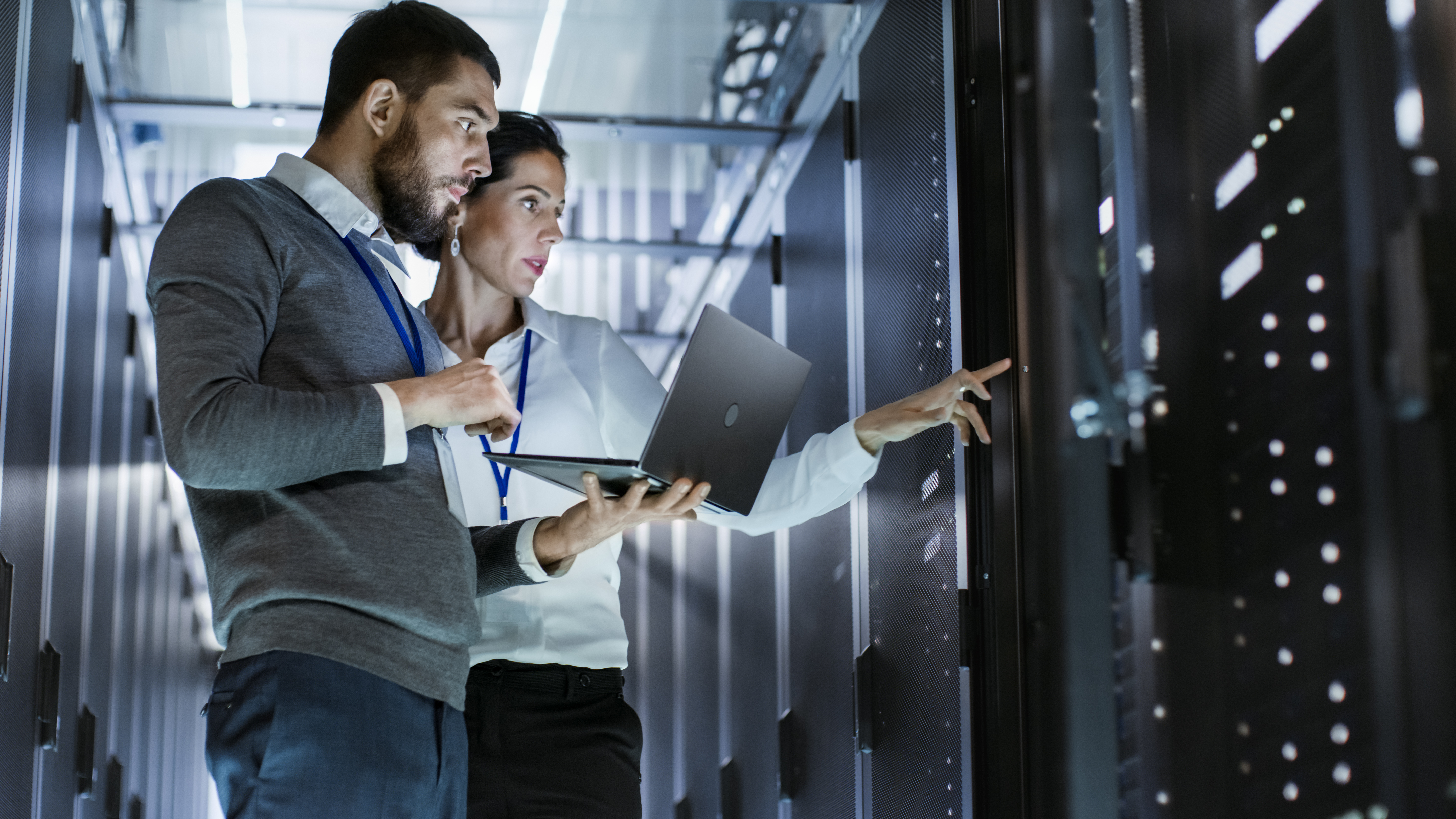 Two professionals working on a laptop and server